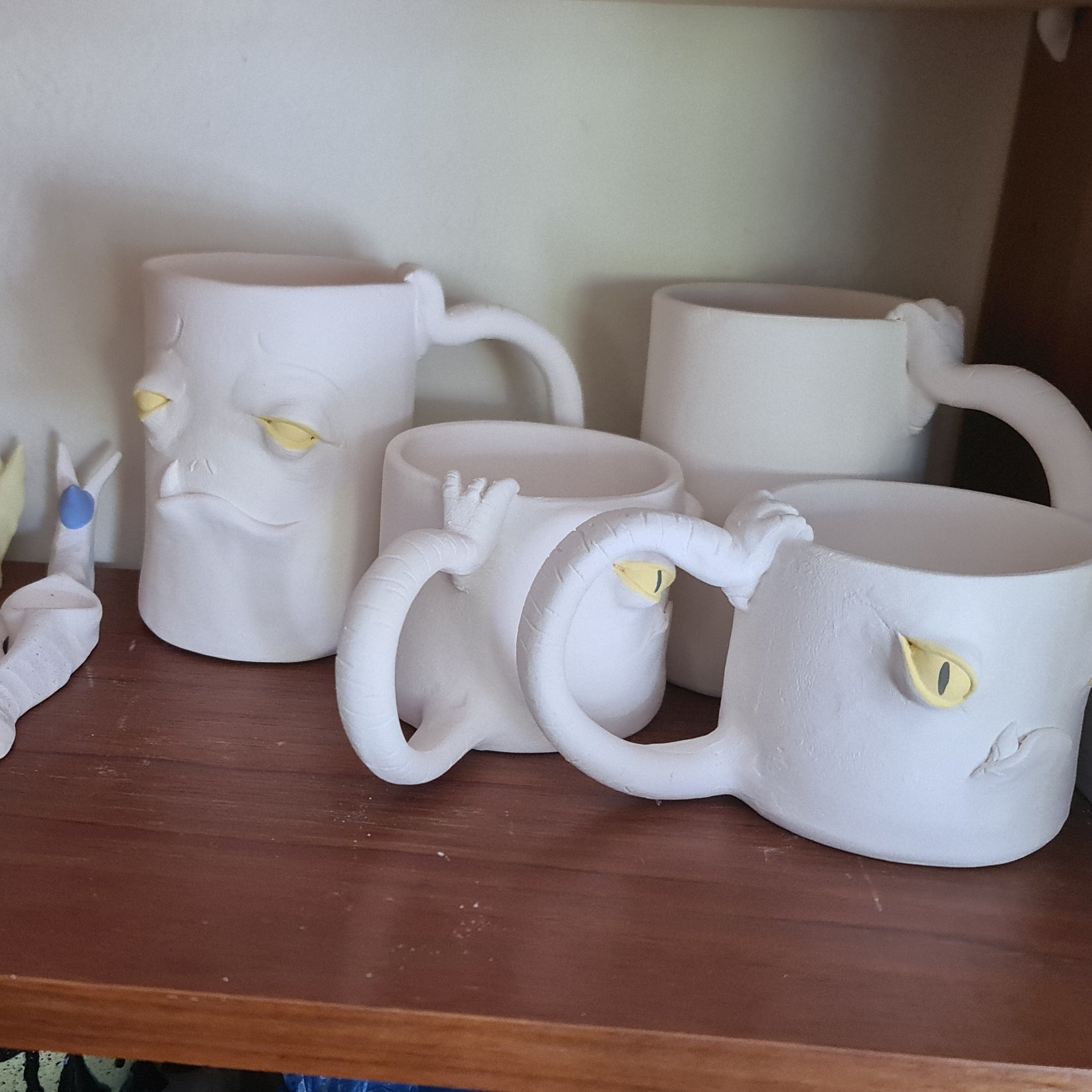 Set of ceramic animal mugs on a wooden shelf